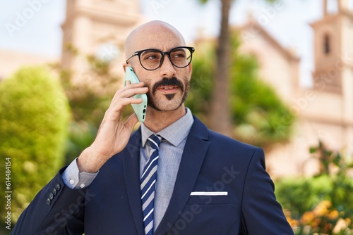 Young hispanic man executive talking on smartphone at park