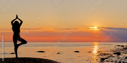 eine Frau zelebriert Yoga bei Sonnenuntergang am Meeresstrand