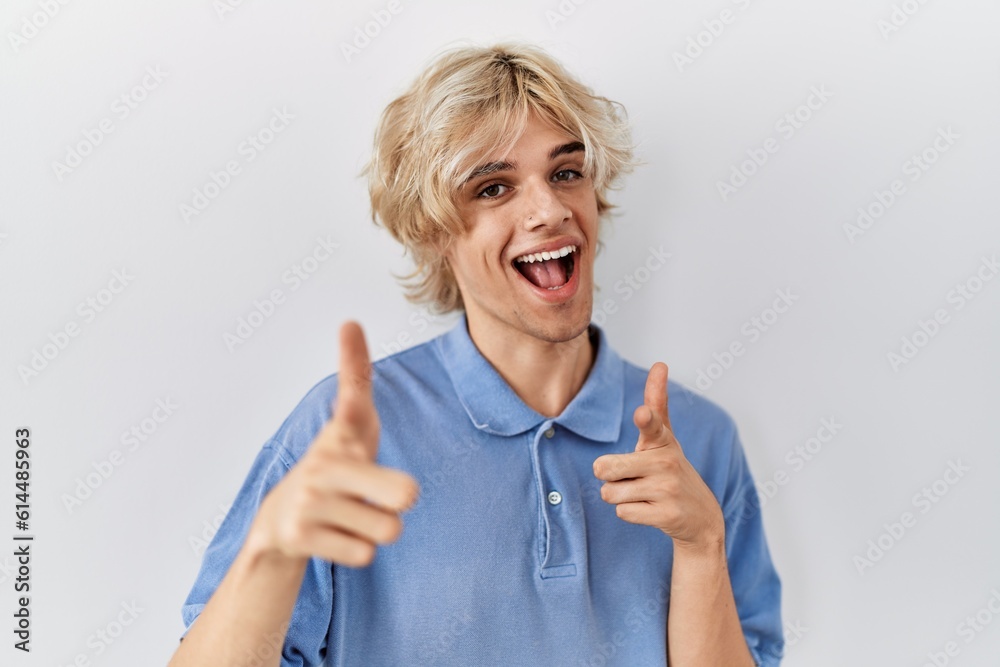 Young modern man standing over isolated background pointing fingers to camera with happy and funny face. good energy and vibes.
