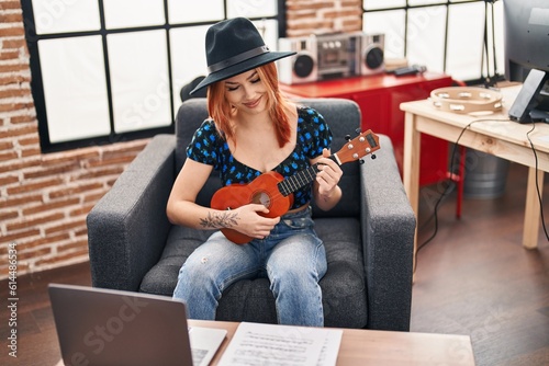 Young caucasian woman musician smiling confident playing ukulele at music studio © Krakenimages.com