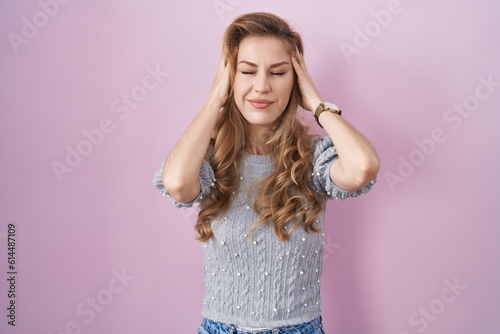 Beautiful blonde woman standing over pink background with hand on head, headache because stress. suffering migraine.