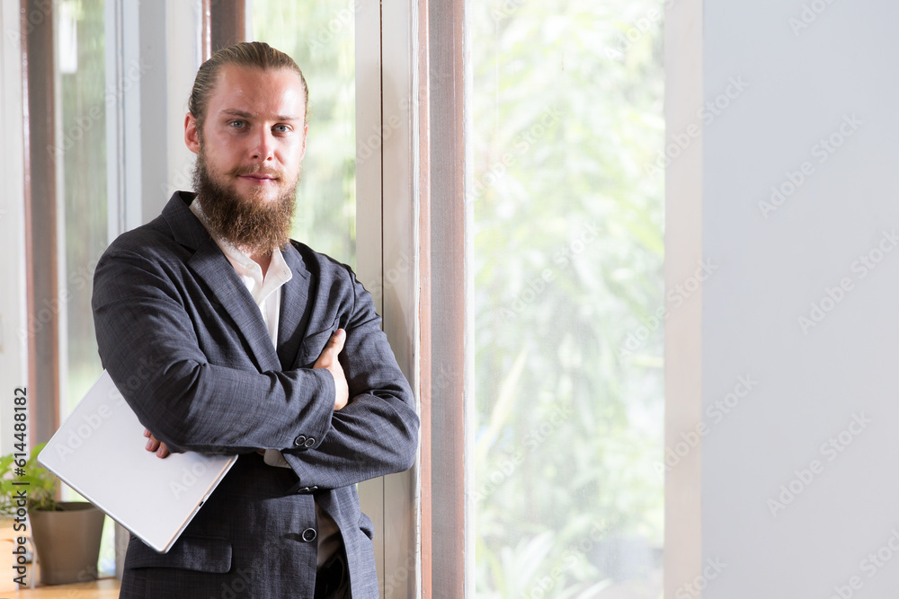 Bearded young businessman holding a tablet and looking at camera with confidence Bearded young businessman holding a tablet and looking at camera with confidence