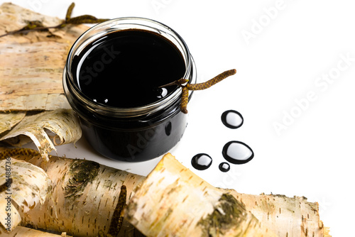 Birch tar or pitch in a jar and birch tree bark on white background. Wood tar. Liquid mineral tar from birch bark