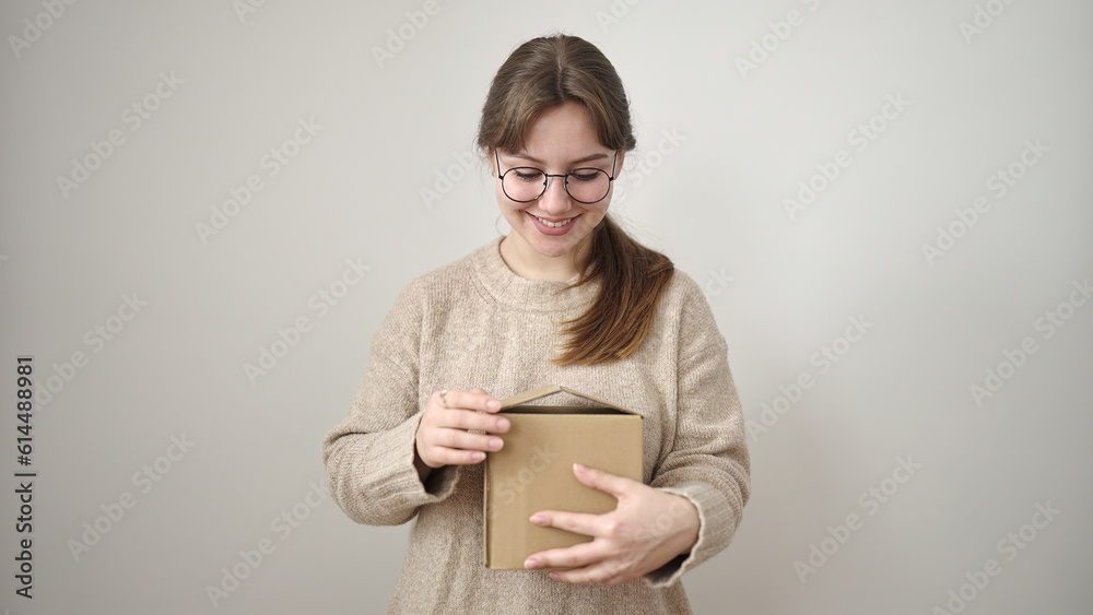Young blonde woman smiling confident unpacking package over isolated white background Young blonde woman smiling confident unpacking package over isolated white background