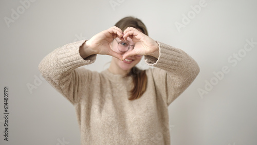 Young blonde woman smiling confident doing heart gesture with hands over isolated white background