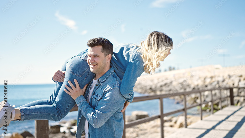 Man and woman couple smiling confident holding girlfriend on air turning at seaside