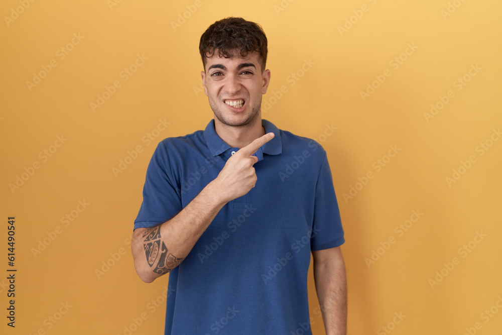 Young hispanic man standing over yellow background pointing aside worried and nervous with forefinger, concerned and surprised expression Young hispanic man standing over yellow background pointing aside worried and nervous with forefinger, concerned and surprised expression