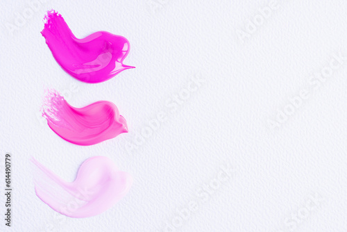 Three smears of different pink paint swatch on white paper background. Bright pink, pink and light pink swatch of lip gloss, cosmetic product stroke or paint