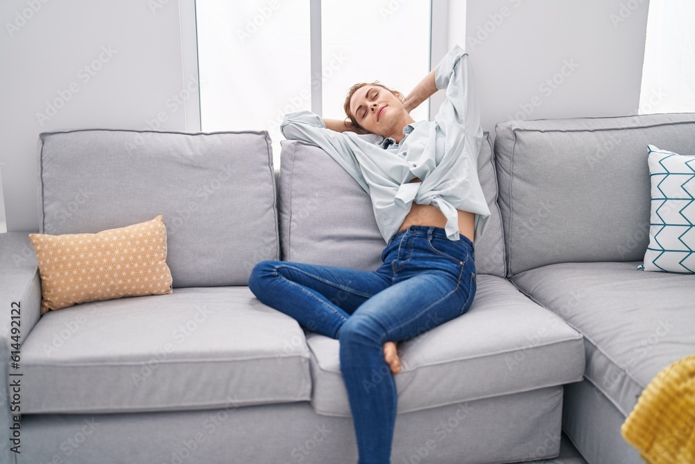 Young woman relaxed with hands on head sitting on sofa at home Young woman relaxed with hands on head sitting on sofa at home