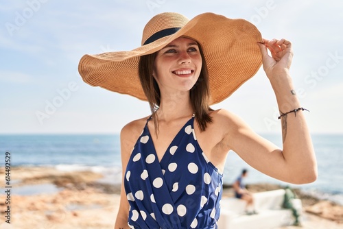 Young blonde woman tourist smiling confident wearing summer hat at beach