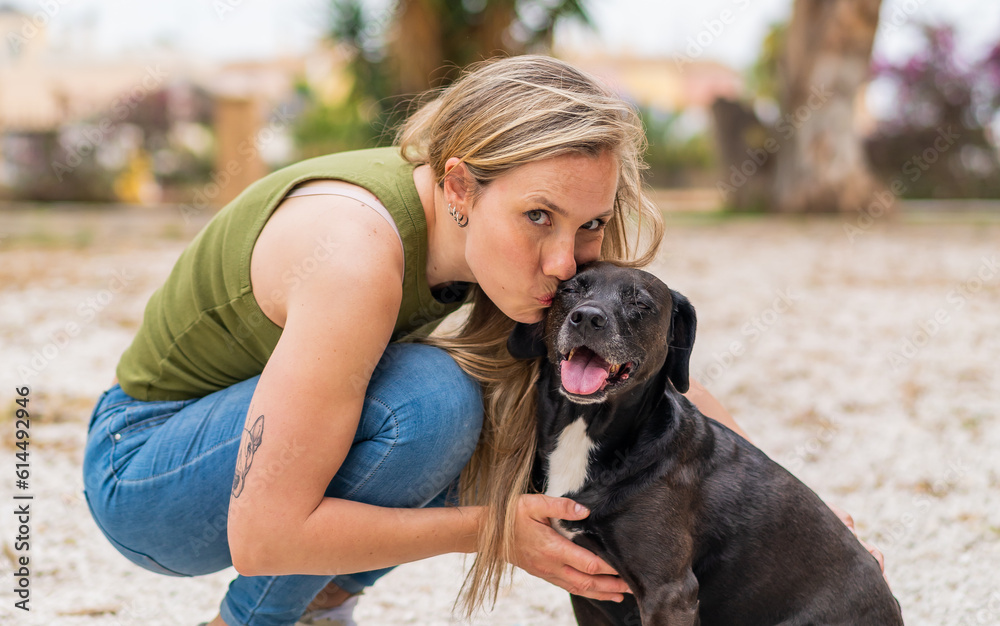 Young blonde woman at outdoors with her adorable black dog Young blonde woman at outdoors with her adorable black dog