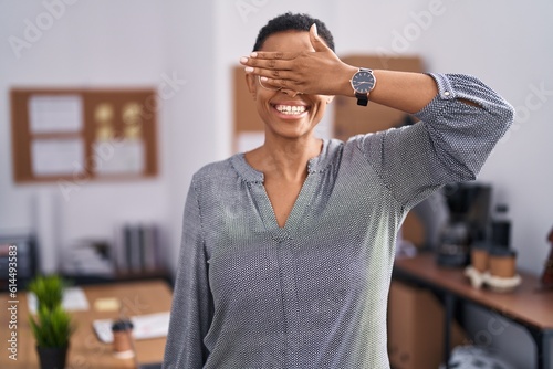 African american woman working at the office wearing glasses smiling and laughing with hand on face covering eyes for surprise. blind concept.