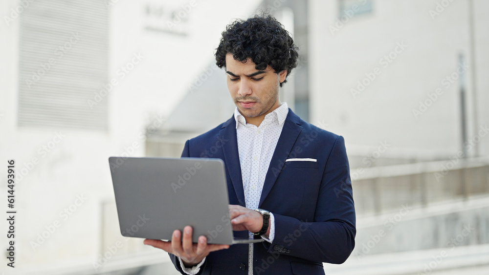 Young latin man business worker using laptop at street