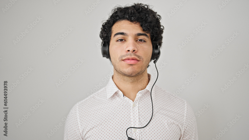 Young latin man business worker wearing headphones over isolated white background - obrazy, fototapety, plakaty 