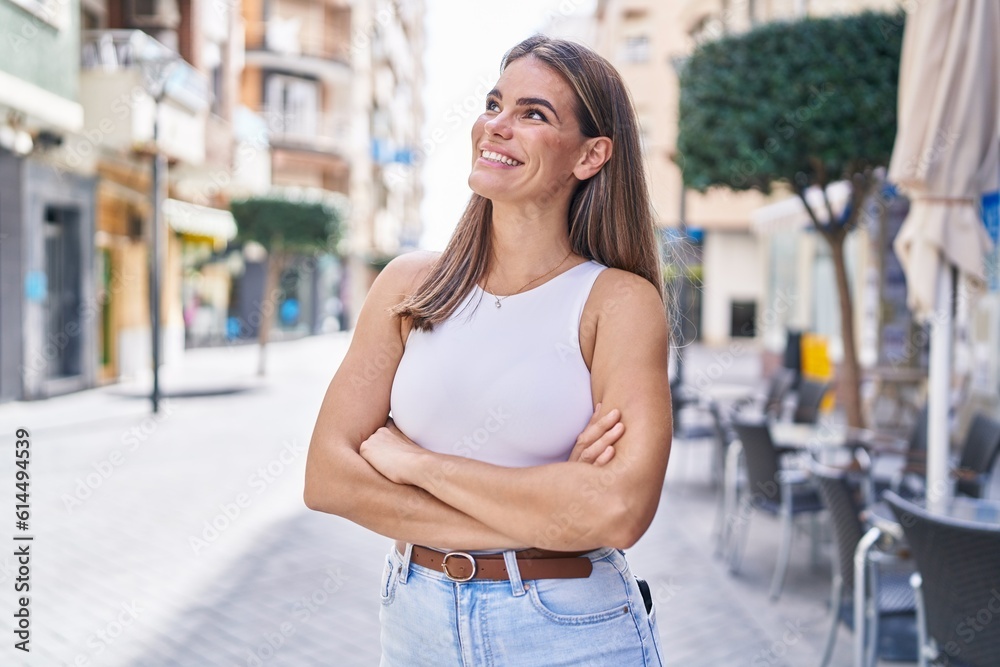 Young beautiful hispanic woman standing with arms crossed gesture looking to the sky at coffee shop terrace