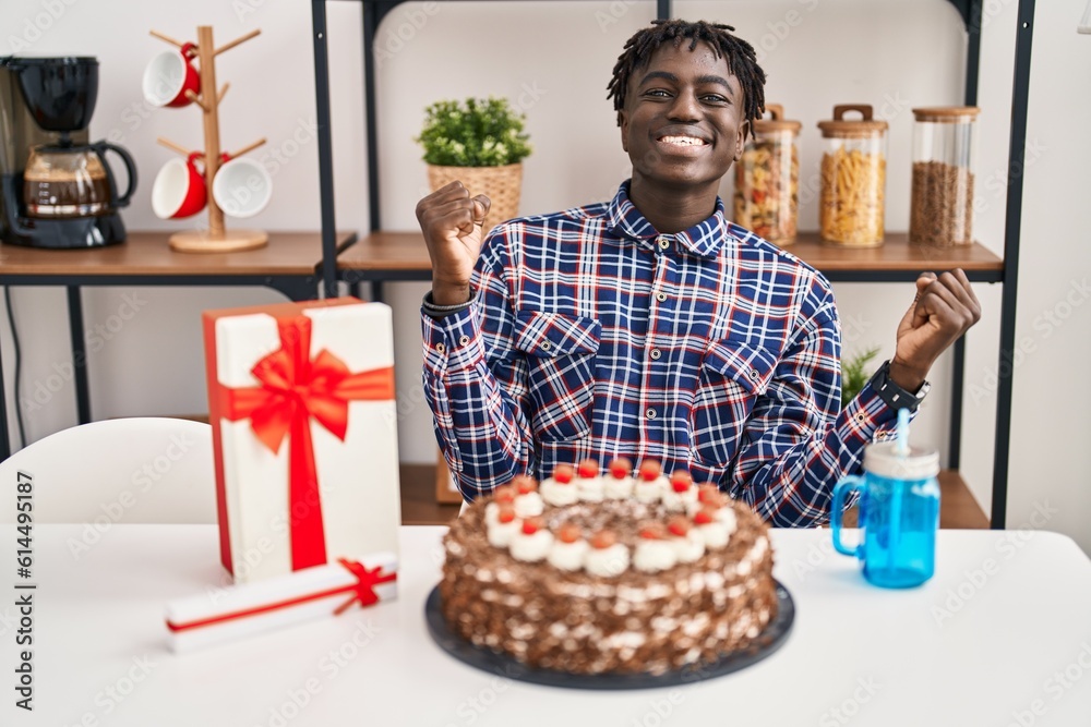 African man with dreadlocks celebrating birthday holding big chocolate cake screaming proud, celebrating victory and success very excited with raised arms African man with dreadlocks celebrating birthday holding big chocolate cake screaming proud, celebrating victory and success very excited with raised arms