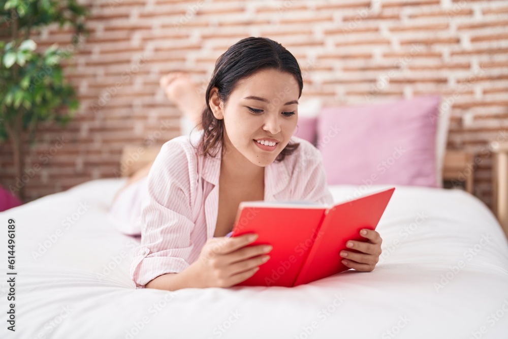 Young hispanic woman reading book lying on bed at bedroom Young hispanic woman reading book lying on bed at bedroom