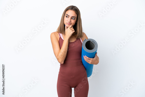 Young sport caucasian woman going to yoga classes isolated on white background having doubts © luismolinero