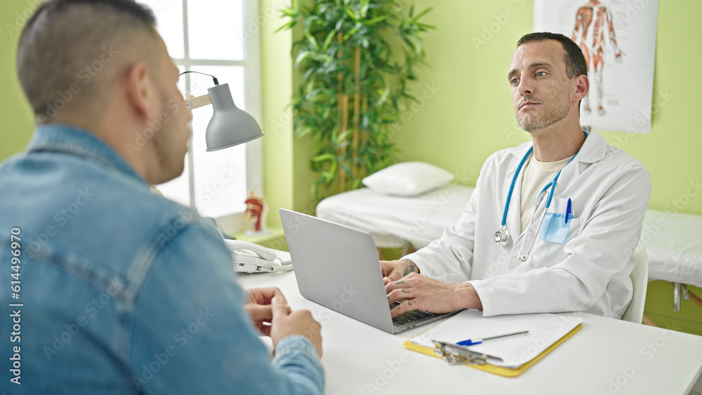 Two men doctor and patient using laptop having medical consultation at clinic Two men doctor and patient using laptop having medical consultation at clinic