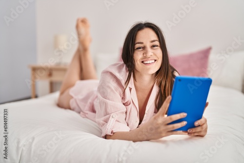 Young woman using touchpad lying on bed at bedroom