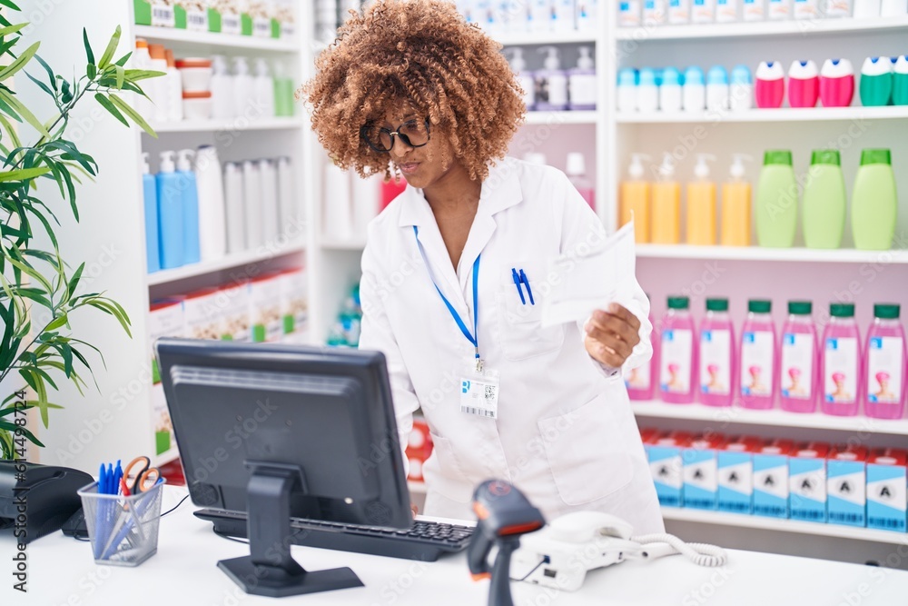 African american woman pharmacist using computer reading prescription at pharmacy