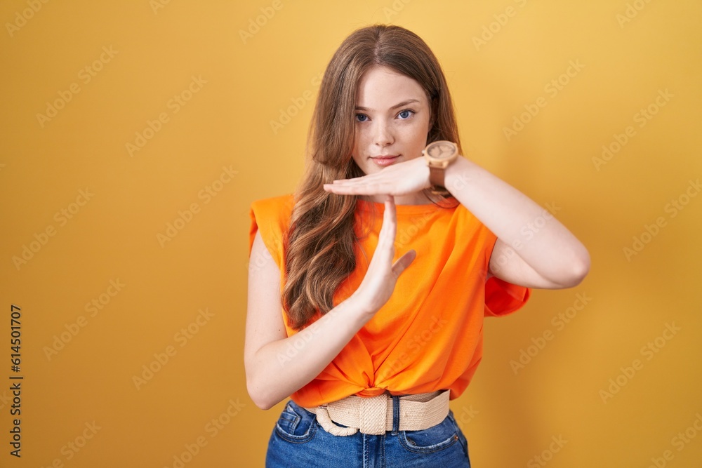 Caucasian woman standing over yellow background doing time out gesture with hands, frustrated and serious face Caucasian woman standing over yellow background doing time out gesture with hands, frustrated and serious face