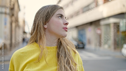 Young blonde woman looking to the side with relaxed expression at street