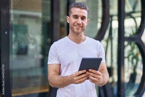 Young caucasian man smiling confident using touchpad at street © Krakenimages.com