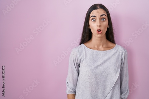 Young brunette woman standing over pink background afraid and shocked with surprise expression, fear and excited face.