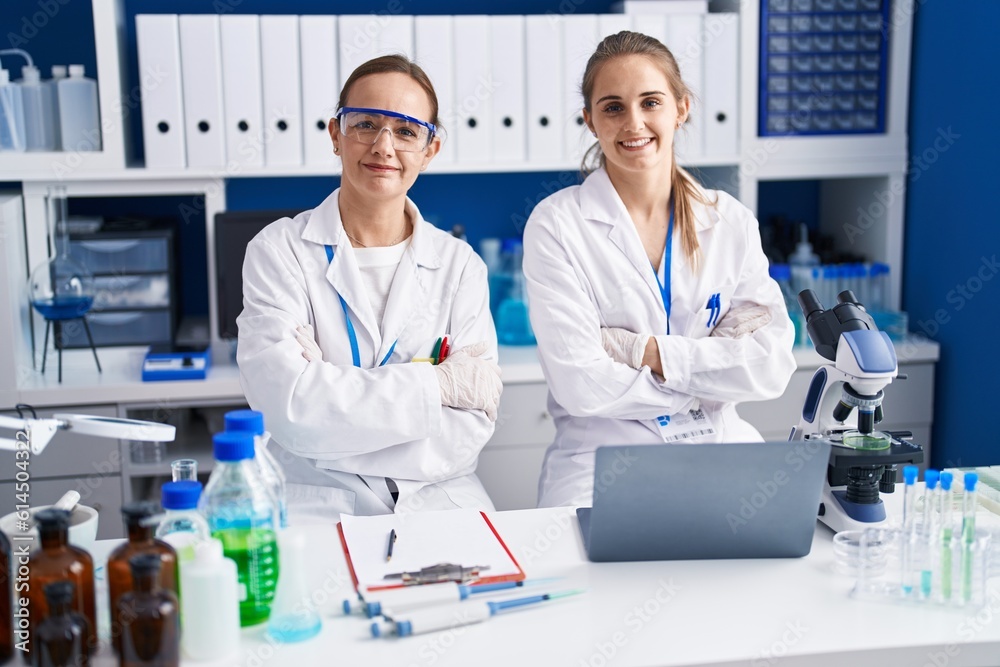 Two women scientists smiling confident with arms crossed gesture at laboratory
