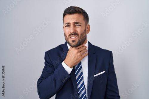 Handsome hispanic man wearing suit and tie touching painful neck, sore throat for flu, clod and infection