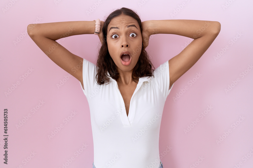 Young hispanic woman wearing casual white t shirt crazy and scared with hands on head, afraid and surprised of shock with open mouth Young hispanic woman wearing casual white t shirt crazy and scared with hands on head, afraid and surprised of shock with open mouth