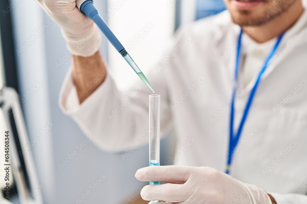 Young hispanic man scientist pouring liquid on test tube at laboratory Young hispanic man scientist pouring liquid on test tube at laboratory