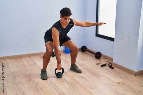 Young hispanic man using kettlebell training at sport center