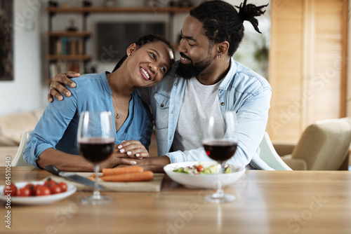 Happy black couple embracing during a meal in dining room