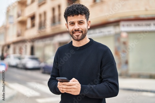 Young arab man smiling confident using smartphone at street photo