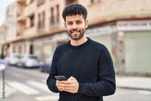 Valokuva Young arab man smiling confident using smartphone at street