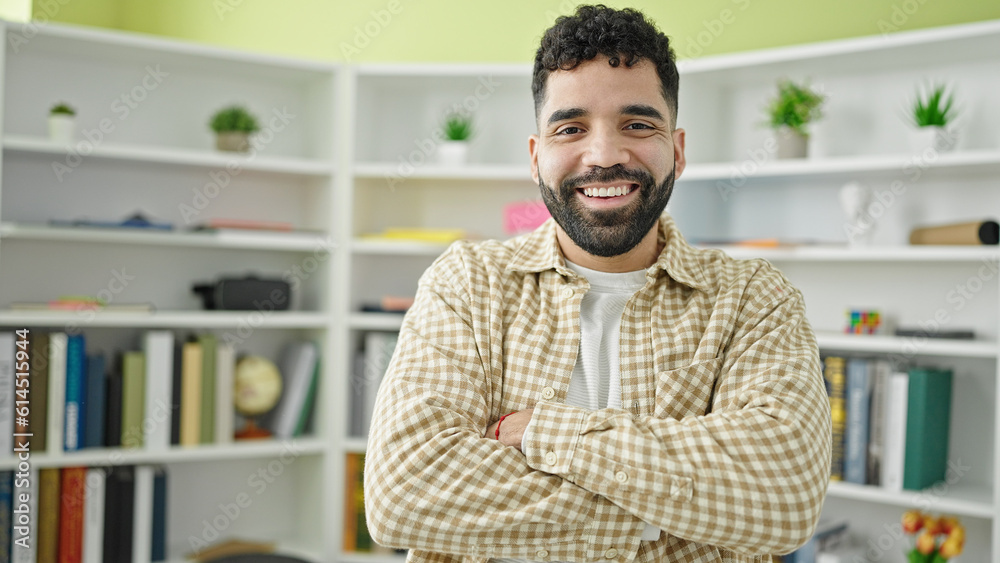 Young hispanic man student smiling confident standing with arms crossed gesture at library university Young hispanic man student smiling confident standing with arms crossed gesture at library university
