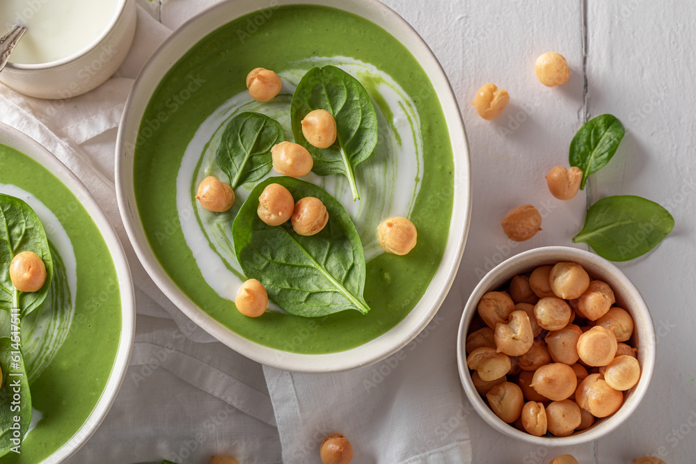 Creamy spinach soup with peas puff, cream and leaves.
