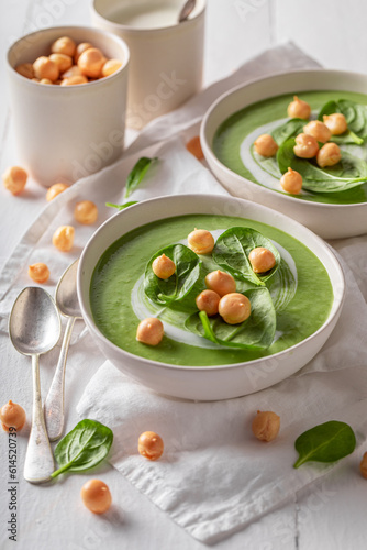 Healthy spinach soup with peas puff, cream and leaves.