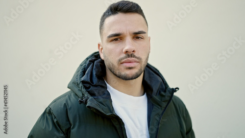 Young hispanic man standing with serious expression over isolated white background