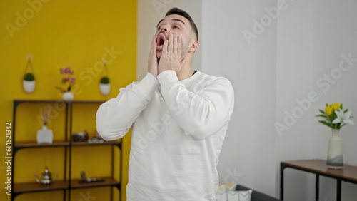 Young hispanic man stressed standing at home