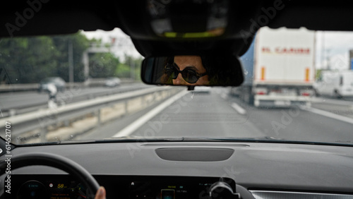 Middle age hispanic woman driving a car wearing sunglasses on the road