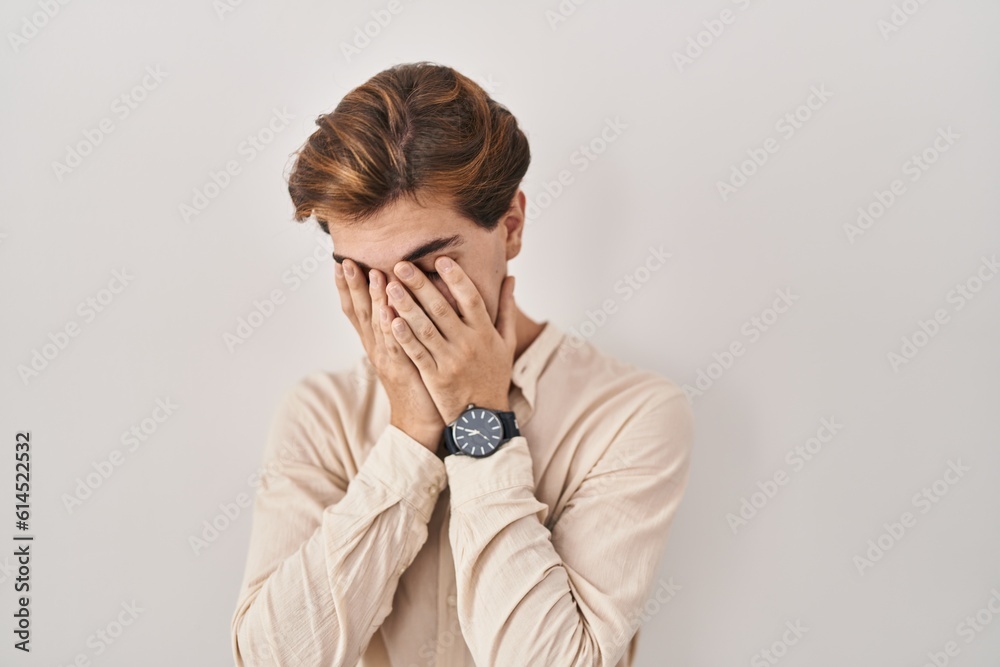 Young man standing over isolated background with sad expression covering face with hands while crying. depression concept. Young man standing over isolated background with sad expression covering face with hands while crying. depression concept.