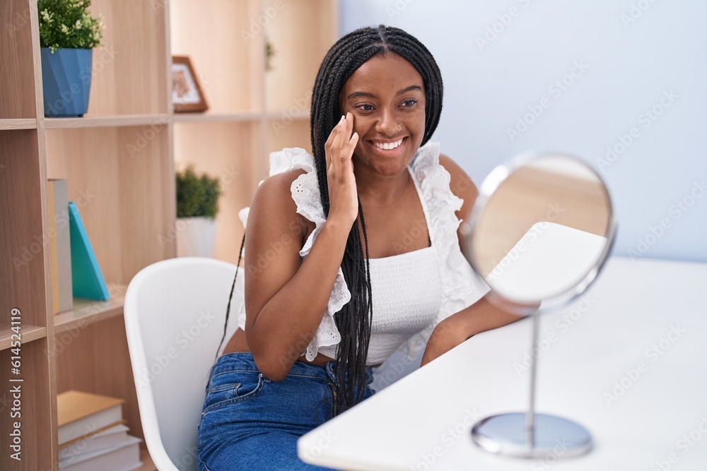 African american woman looking face on mirror sitting on table at home African american woman looking face on mirror sitting on table at home