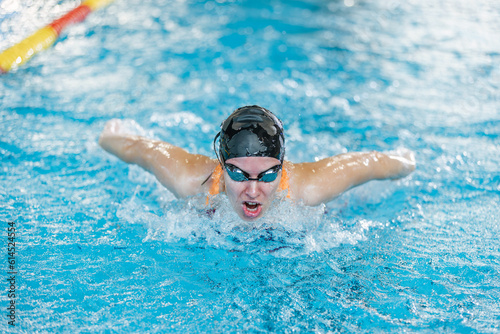 Female competitive swimmer moving through the water performing the butterfly stroke during swimming training, front view. © 24K-Production
