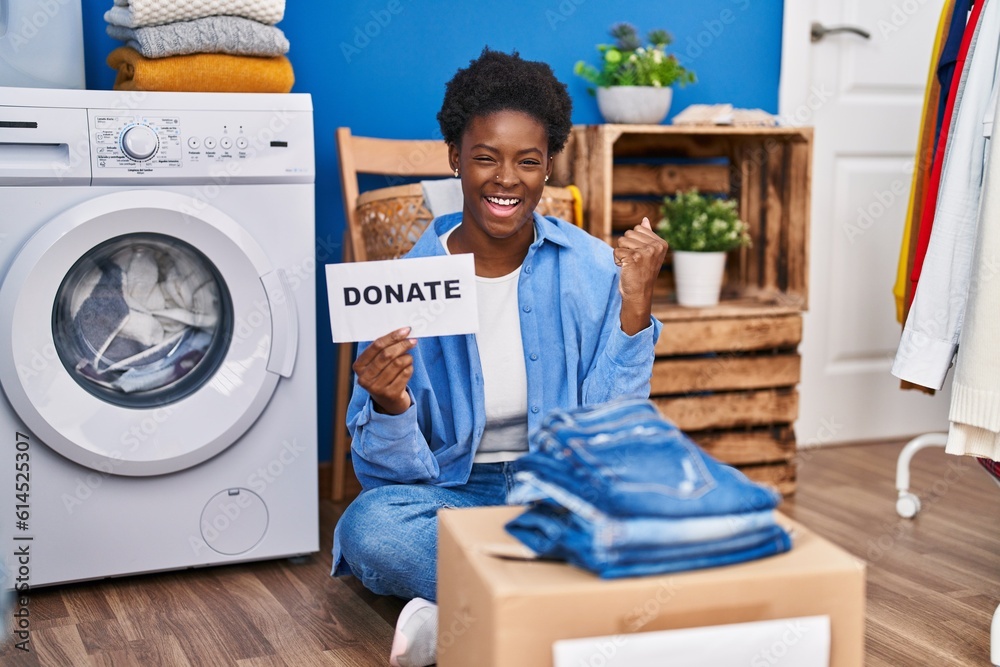 African american woman donating clothes screaming proud, celebrating victory and success very excited with raised arms African american woman donating clothes screaming proud, celebrating victory and success very excited with raised arms