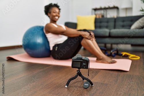 African american woman recording video sitting on yoga mat at home