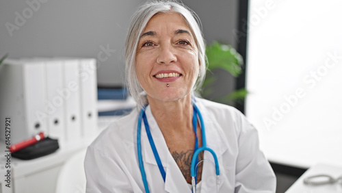 Foto Middle age grey-haired woman doctor smiling confident working at clinic