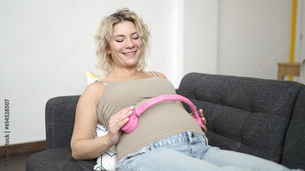 Young pregnant woman smiling confident putting headphones on belly at home Young pregnant woman smiling confident putting headphones on belly at home